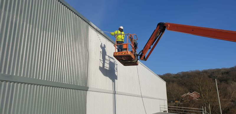 ProCoating team spraying cladding from a cherry picker on an industrial unit